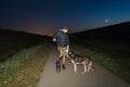 A man on an electric scooter rides with a husky dog Ã¢â¬â¹Ã¢â¬â¹on a leash at night under a starry sky